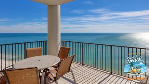 Un balcon avec une table et des chaises, donnant sur une mer d’un bleu limpide.