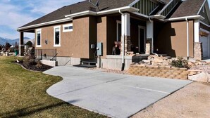 A modern two-story house with a covered porch, a driveway, and a landscaped front yard. - Montague Manor" W&D, Hot Tub, Queen Beds, Sleeps6 (Bluffdale)