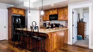 A kitchen with wooden cabinets, a black refrigerator, a microwave, and a granite countertop. - Montague Manor" W&D, Hot Tub, Queen Beds, Sleeps6 (Bluffdale)