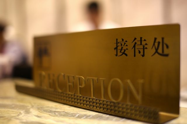 A reception desk with a sign that reads 'RECEPTION' and another sign with Chinese characters.