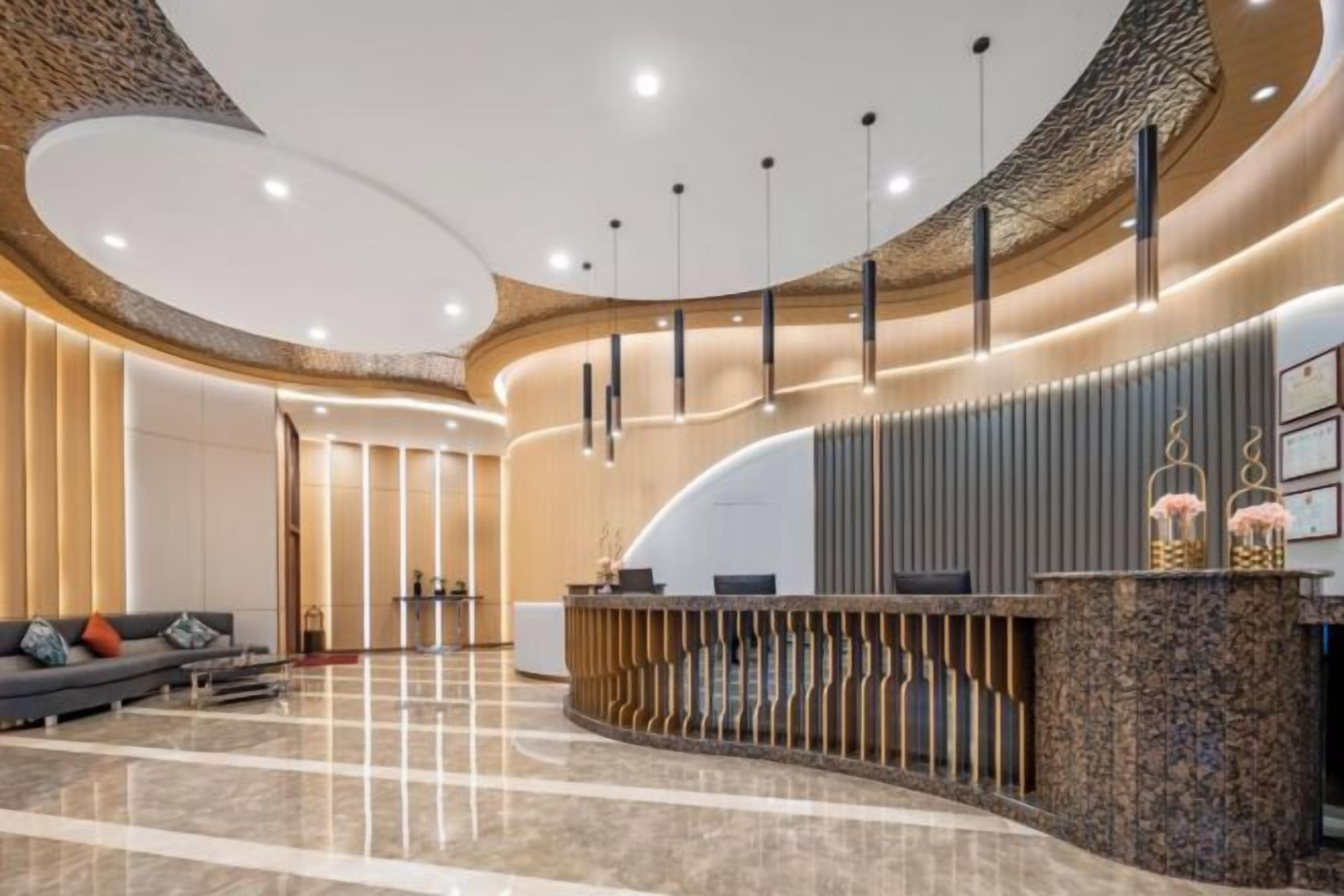 A modern reception area with a curved reception desk, a seating area with a sofa, and a polished marble floor.