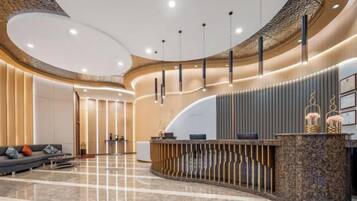 A modern reception area with a curved reception desk, a seating area with a sofa, and a polished marble floor.