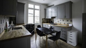 Una cuina moderna amb armaris grisos, taulell de fusta i taula de dinar negra amb cadires.