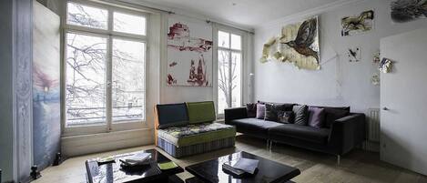 A modern living room with a sofa, coffee tables, and artwork on the walls.