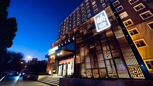 Un moderno edificio de hotel con un letrero llamativo, varios pisos y una entrada bien iluminada.