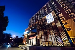 Ein modernes Hotelgebäude mit einer auffälligen Beschilderung, mehreren Stockwerken und einem gut beleuchteten Eingang.
