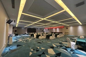 A conference room with a geometric patterned carpet, rows of tables with chairs, and a stage with a red banner. - Yitel Premium Beijing Wangjing 798 (Beijing)