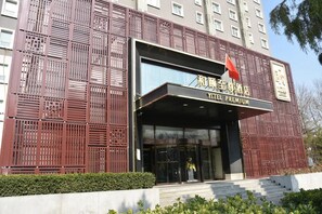 A hotel entrance with a modern facade, a flag, and a sign indicating it is a premium hotel. - Yitel Premium Beijing Wangjing 798 (Beijing)