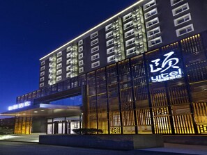 A modern hotel building with a prominent entrance and illuminated signage.