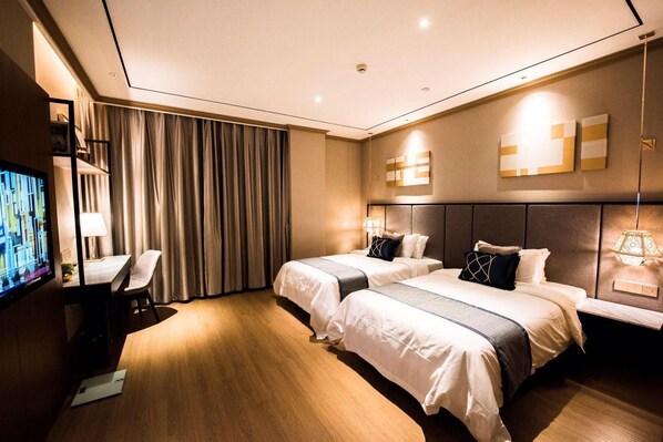 A hotel room with two beds, a desk, and a television.