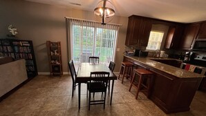 Una cocina con mesa de comedor, sillas, barra y horno empotrado.