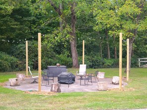 Un espacio al aire libre con mesas y sillas, rodeado de árboles y una valla de madera.