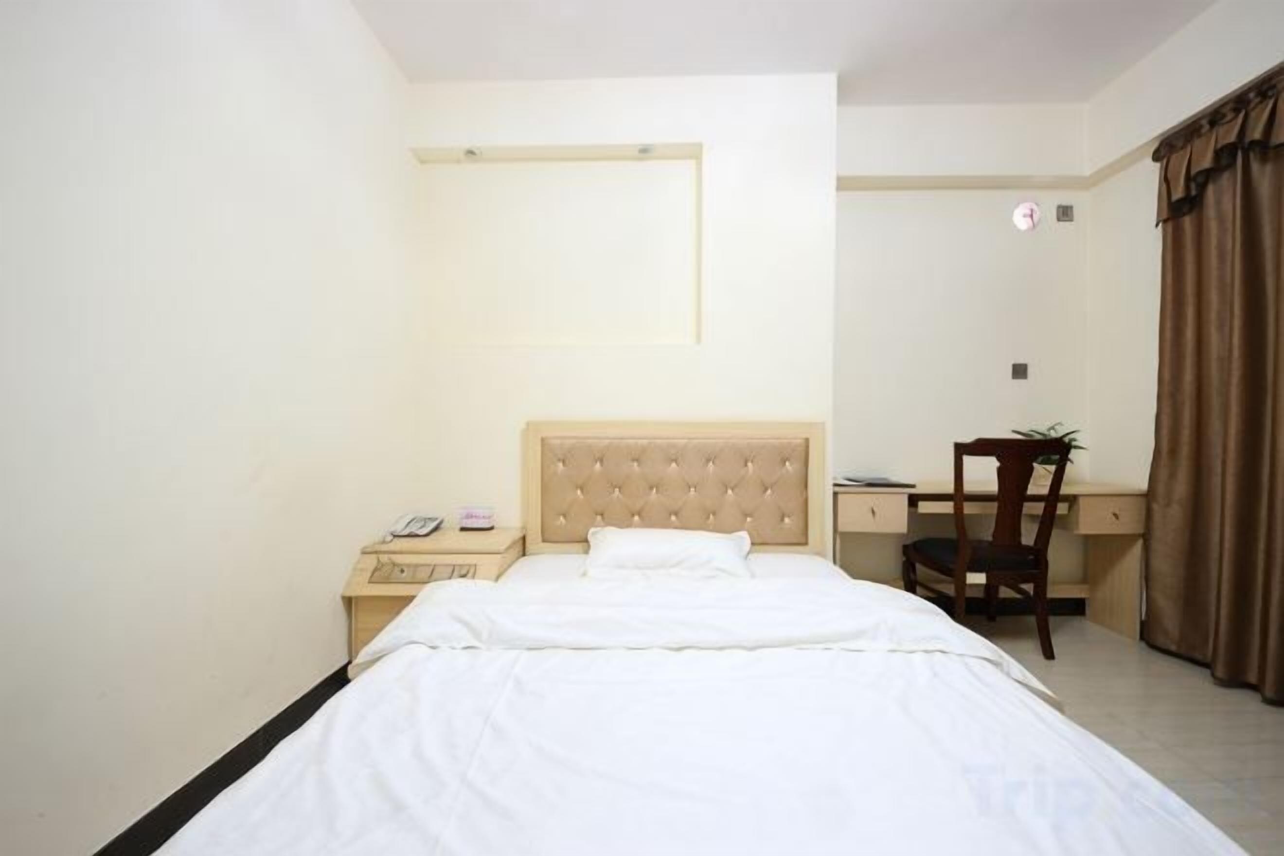 Une chambre d’hôtel équipée d’un lit, d’un bureau, d’une chaise, d’un téléphone et d’un miroir.