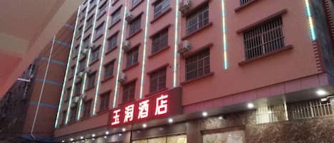 Un hotel a più piani con facciata rossa e insegne illuminate.