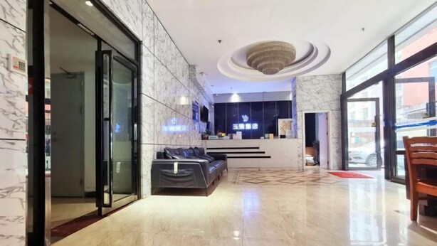 Eine Hotelhalle mit Empfangsschalter, einer Sitzecke und einem modernen Deckenstil.