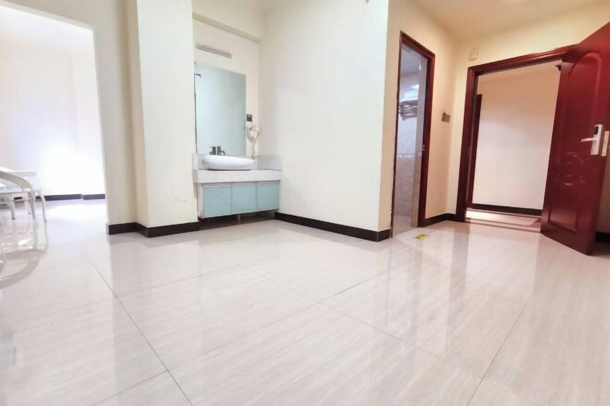 Un couloir d’hôtel avec une salle de bain moderne équipée d’un lavabo et d’un miroir.