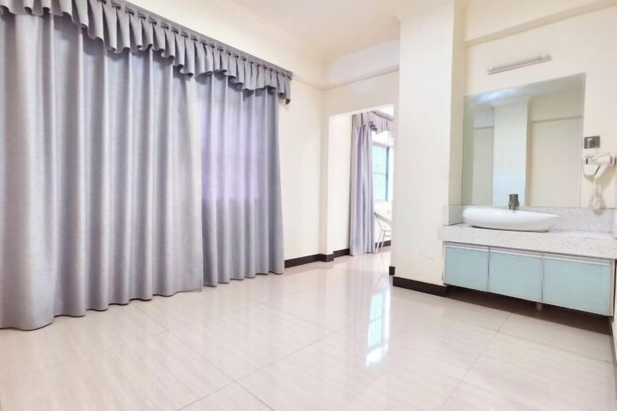 A hotel room with a large window, a bathroom with a sink and mirror, and a curtain covering the window.