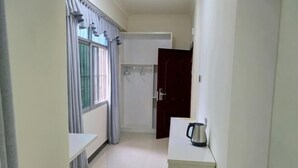 Ein schmaler Flur mit Fenster, Kleiderhaken und einer Tür.