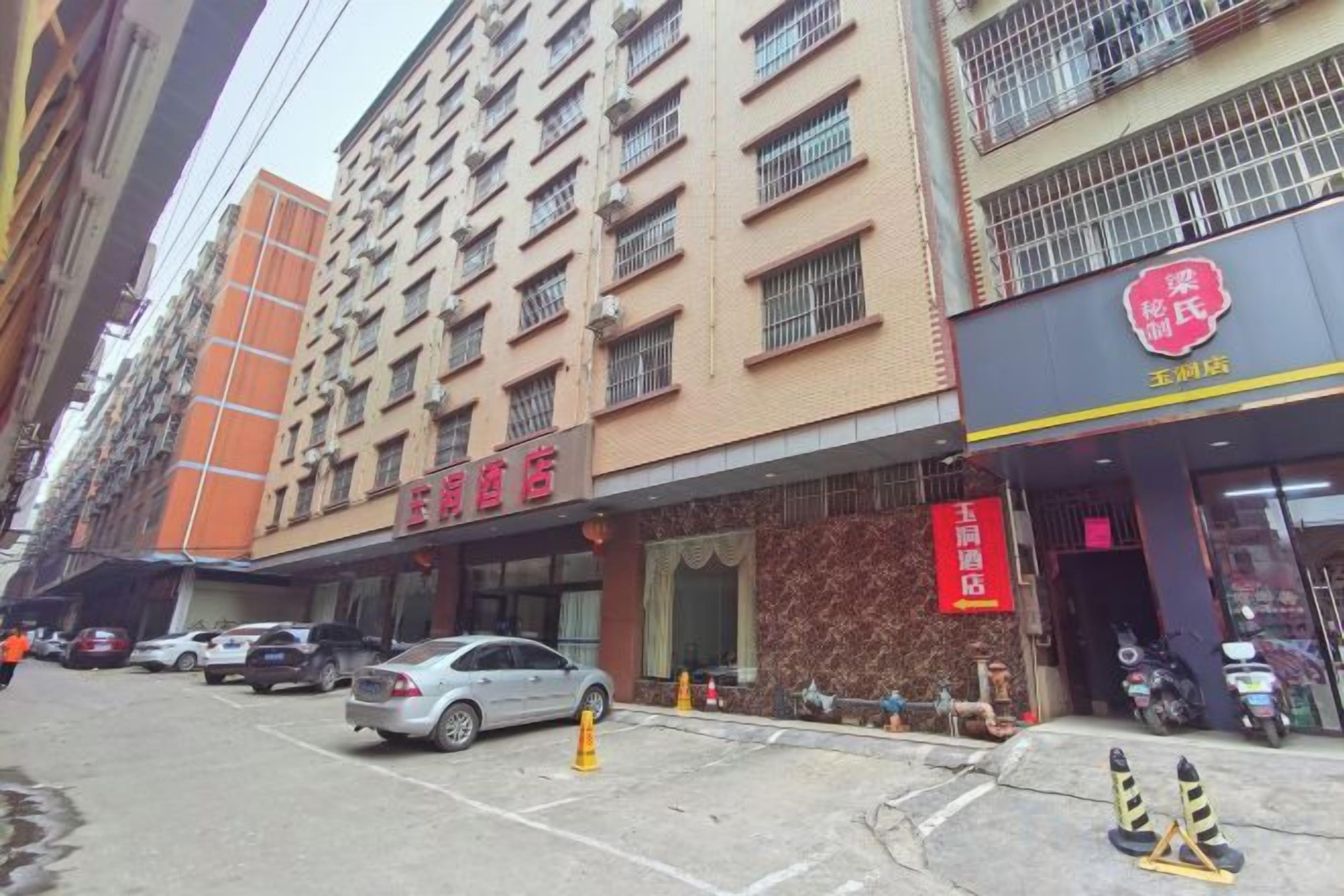 A multi-story hotel with a visible entrance and parked cars.