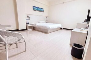 Ein Hotelzimmer mit Bett, Schreibtisch, Stuhl und Mülleimer.