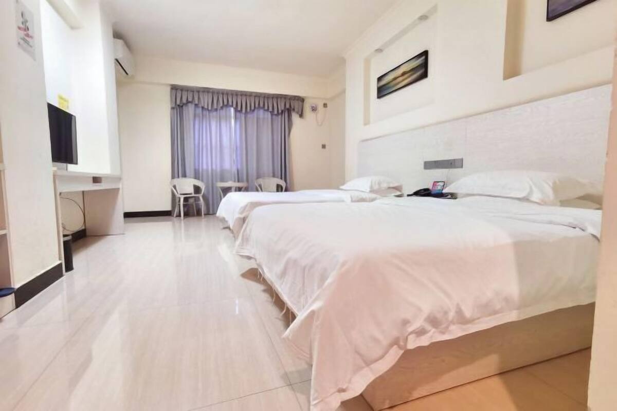 Une chambre d’hôtel avec deux lits, un bureau, une chaise et un téléviseur.