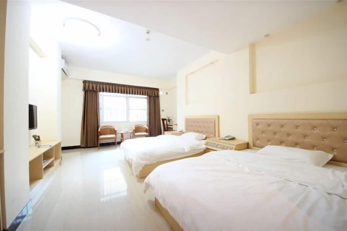 Une chambre d’hôtel avec deux lits, un bureau, une chaise et un téléviseur.