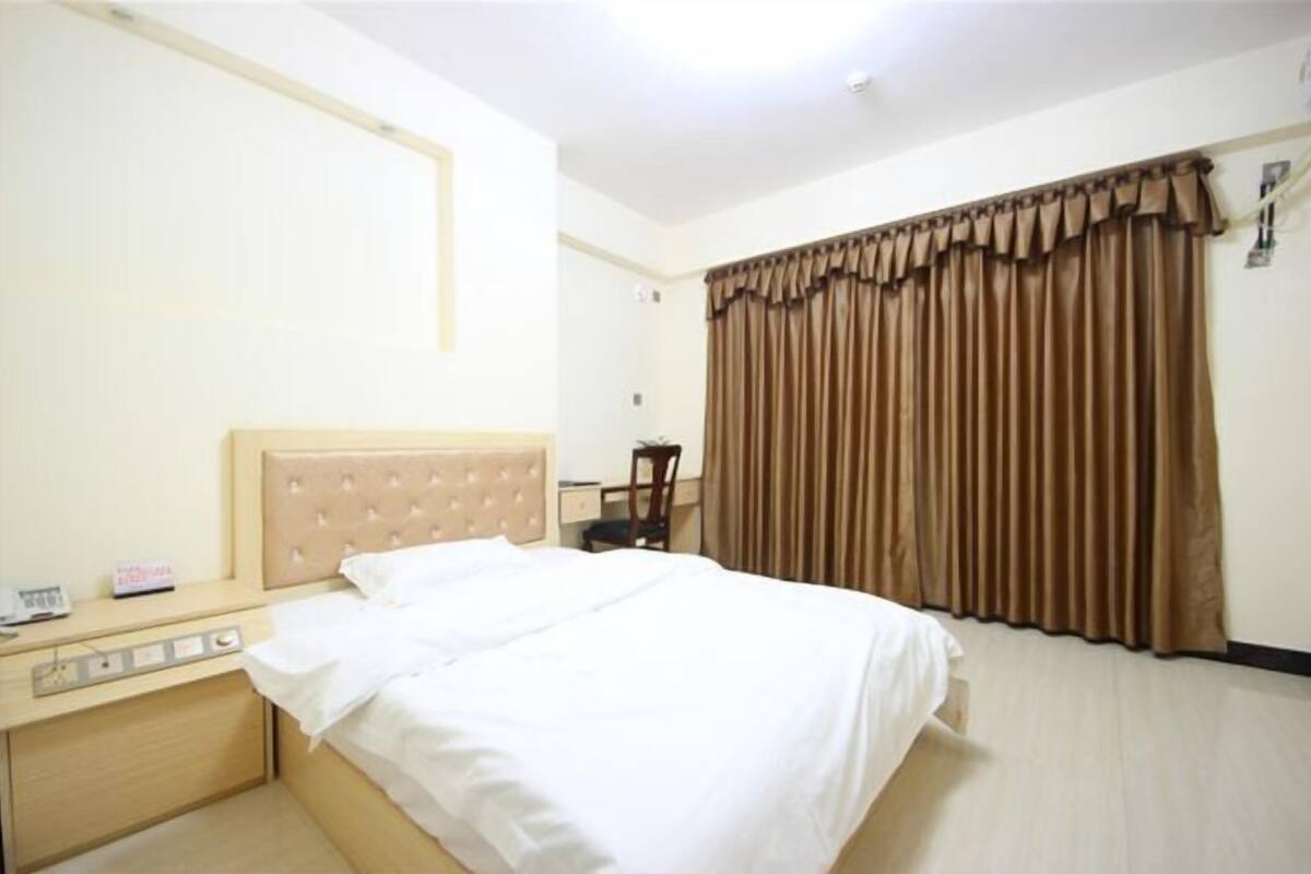 Une chambre d’hôtel avec un lit, une table de chevet et une fenêtre avec des rideaux.