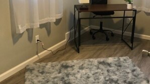 Ein Zimmer mit Schreibtisch, Stuhl und einem grauen Shag-Teppich.