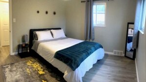 Ein Schlafzimmer mit Bett, Nachttisch, Fenster und Tür.