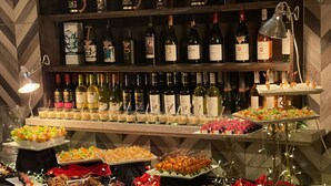 A buffet table with various food items and a selection of wine bottles.