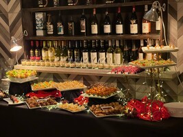 Una mesa de bufé con diferentes platillos y una selección de botellas de vino.