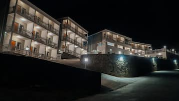 Un hotel de varios pisos con balcones, un muro de piedra y un sendero pavimentado.