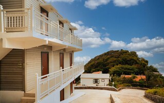 Un hotel con balcón, vistas a una colina y cielo despejado.
