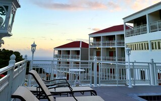 Un hotel con varios balcones, mobiliario exterior y vista al mar.