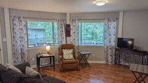 A living room with a sofa, a chair, a TV, and a small table. - DOUBLE DECKER CONDO! LARGE GROUPS! NEXT TO CAMPUS! (Oxford)