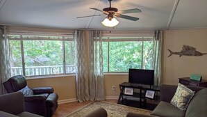 A living room with a ceiling fan, a TV on a stand, and a fish wall decoration. - DOUBLE DECKER CONDO! LARGE GROUPS! NEXT TO CAMPUS! (Oxford)