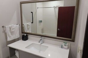 A bathroom with a white sink, a large mirror, and a towel rack with white towels.