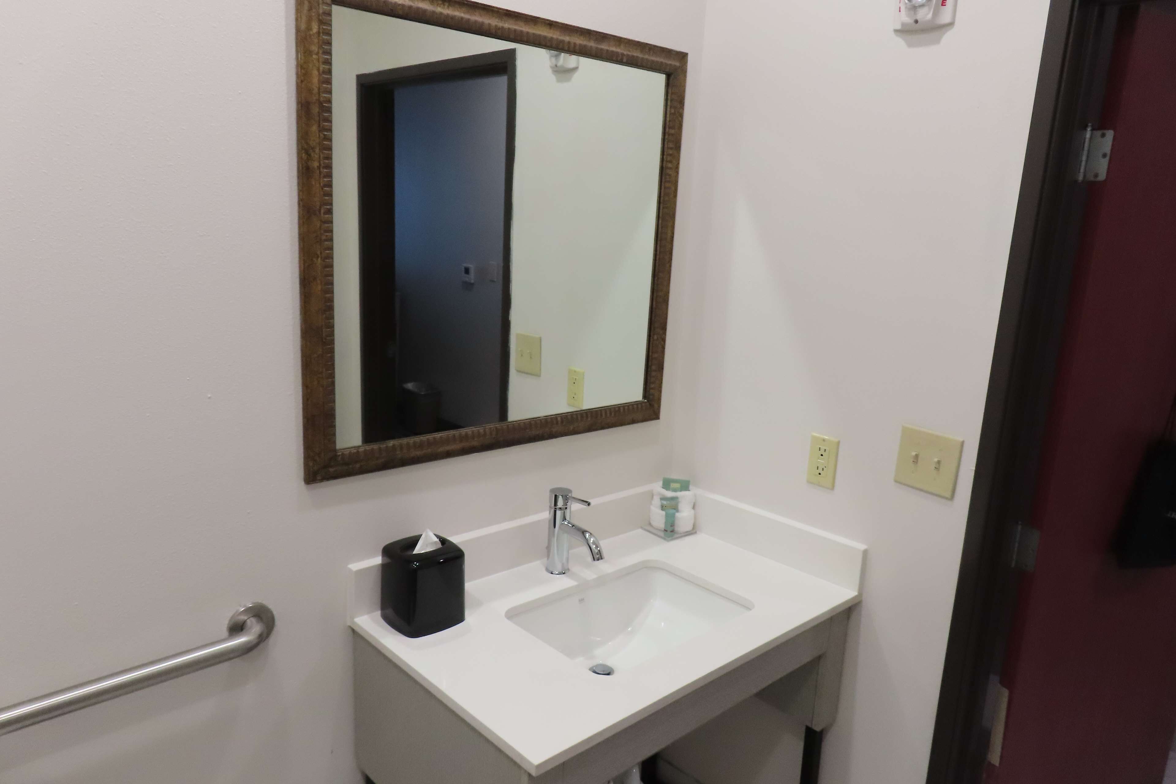 A bathroom with a white sink, a mirror, a towel dispenser, and a hand dryer.
