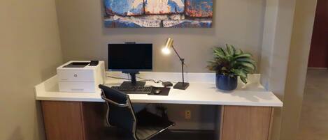 A modern office desk with a computer, printer, and a potted plant.