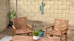 A wooden table and two chairs with a cactus wall in the background. - Cactus Oasis -Cheerful 3 bedroom family home with heated pool. (Phoenix)