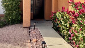 A house with a brown exterior, a dark brown door, and a small porch area. - Cactus Oasis -Cheerful 3 bedroom family home with heated pool. (Phoenix)