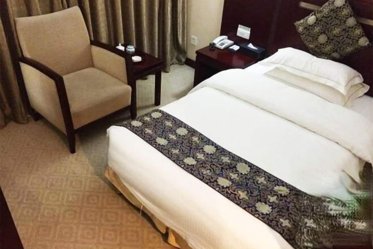 A hotel room with a bed, a chair, a nightstand, and a telephone.