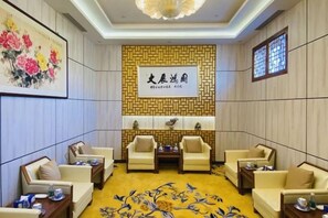Un salón de conferencias con una pared estampada, una obra de arte grande enmarcadas y una alfombra con diseño floral.