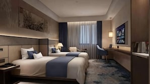 A hotel room with two beds, a desk, a chair, a lamp, and a large window with curtains. - Beijing Post & Telecom Conference Centre (Beijing)