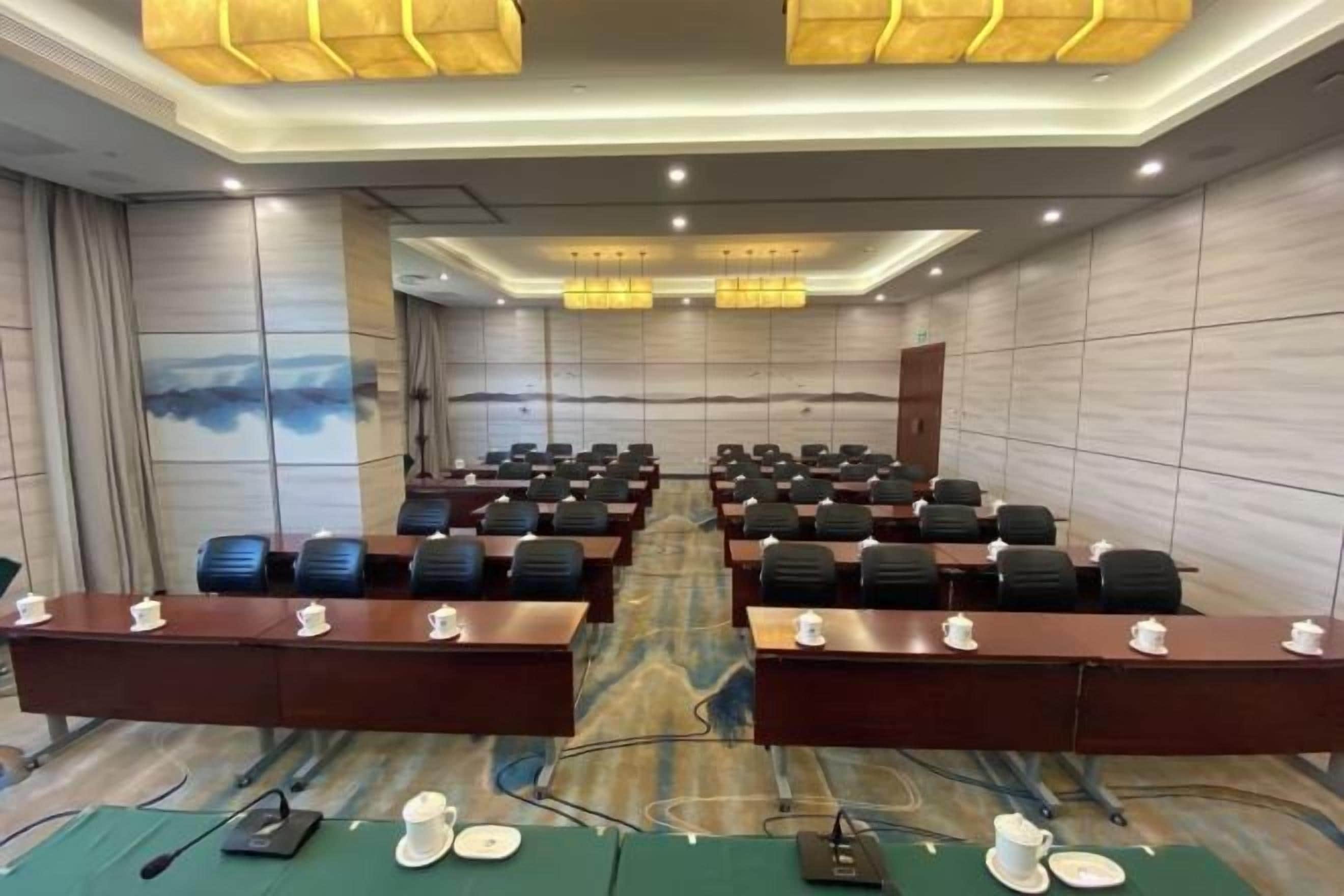 A conference room with rows of tables and chairs, equipped with microphones and nameplates.
