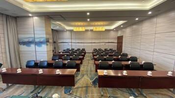 A conference room with rows of tables and chairs, equipped with microphones and nameplates.