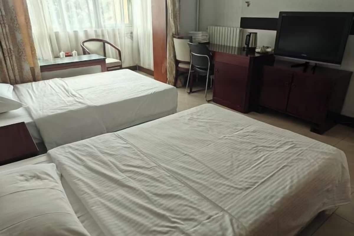 Une chambre dâhĂŽtel avec deux lits, un bureau, une chaise, une tĂ©lĂ©vision et un placard.