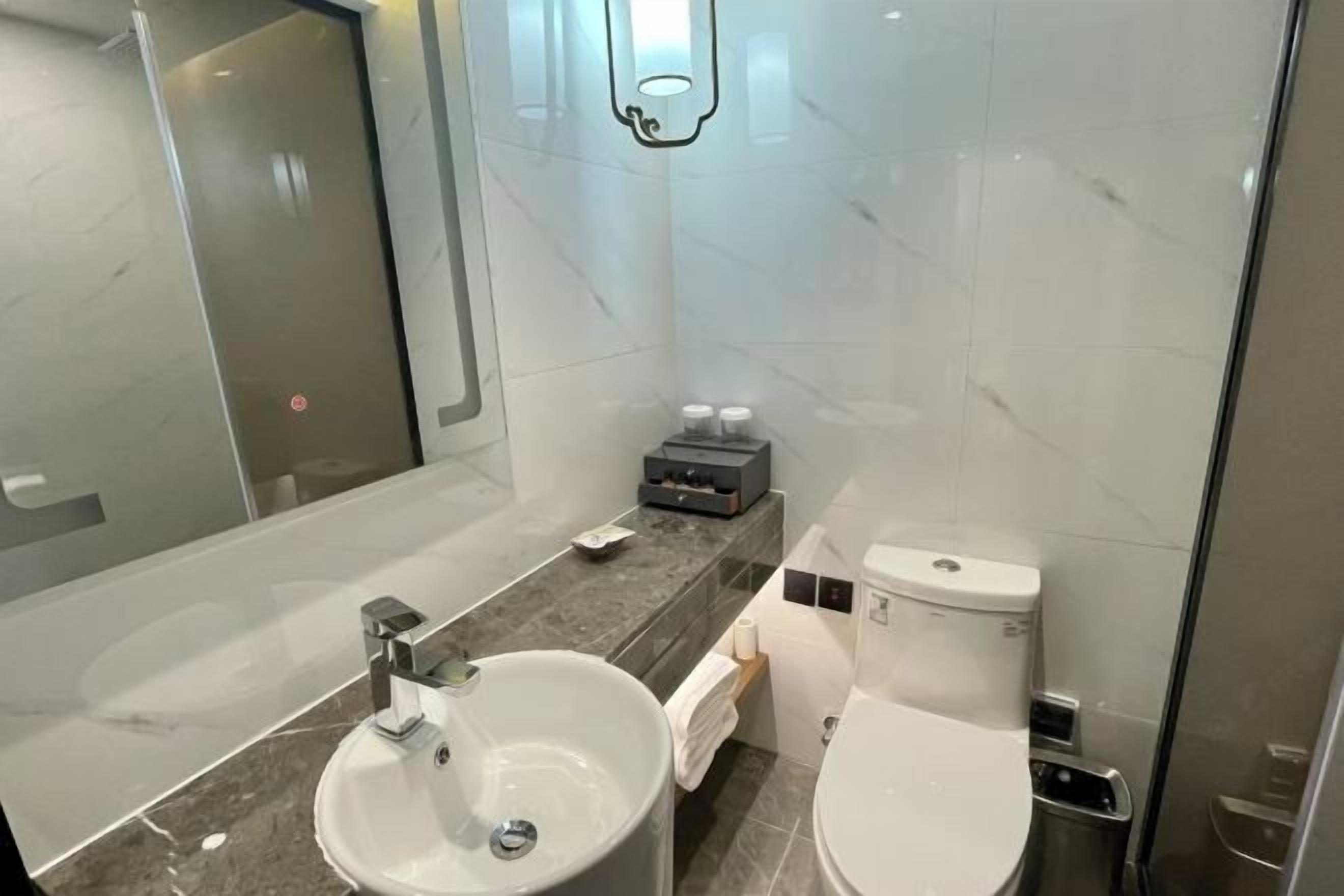 Un baño moderno con un lavamanos grande, inodoro y cabina de ducha con mampara de vidrio.