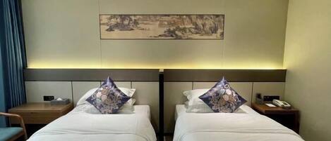Habitación de hotel con dos camas, una mesita de noche con un teléfono y un cuadro en la pared.