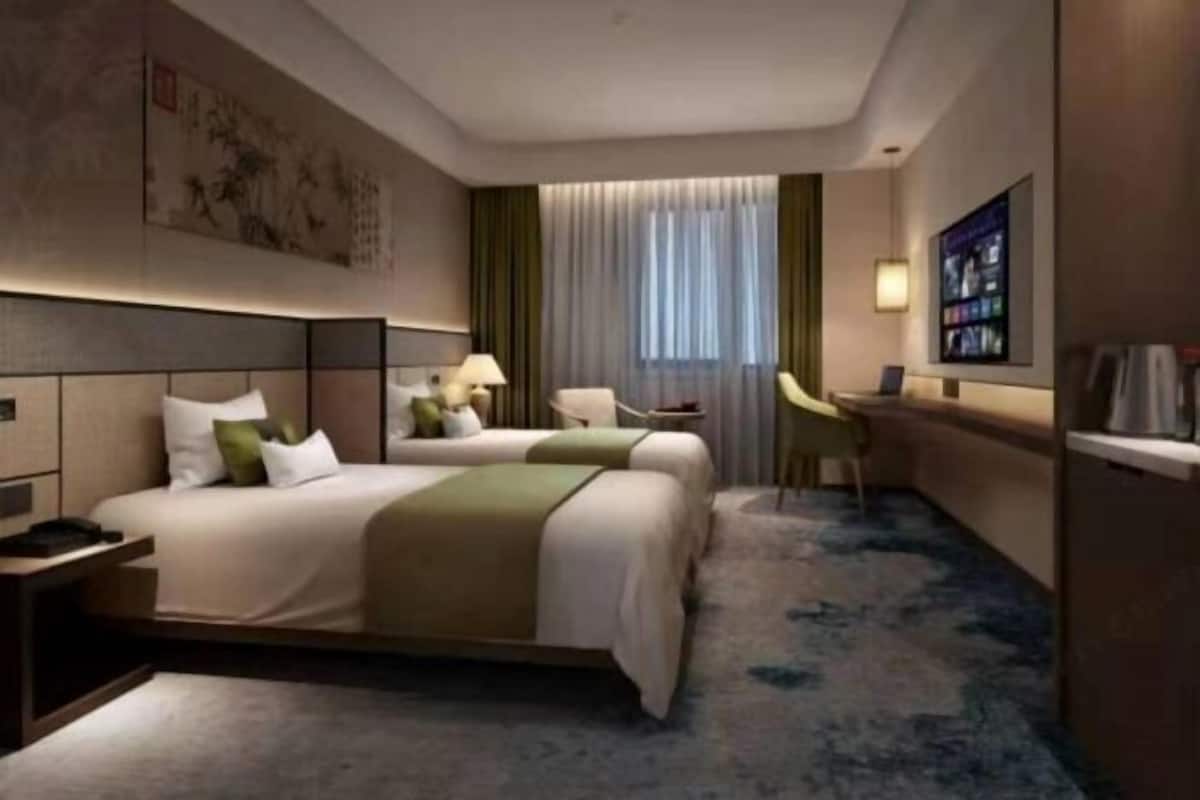 A hotel room with a large bed, a desk, a chair, and a television.